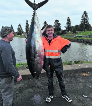 Joe from Game on Fishing Charters looks on as Tom hugs his 100 kg tuna that he and the crew landed.