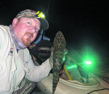 The author snaps a selfie after a successful night raid, with one fish kept for dinner.
