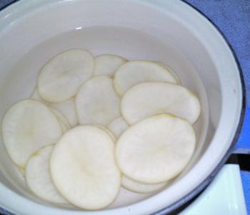 Finely slice (3-4mm) a couple of washed and scrubbed potatoes. Place the potato slices in a saucepan of cold water and bring to a boil. When the water is boiled, remove the saucepan from the heat and drain the water. Place the potato slices onto a paper t