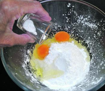 In a large bowl, add the cornflour to the flour. Crack the eggs into the bowl and add the bicarb soda. Grind a generous amount of salt and about a teaspoon of pepper into the bowl. 