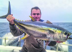 A happy customer aboard Topcat Charters with a typical size yellowfin.