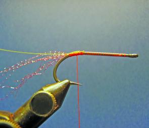 Place the hook in the vice and attach the thread, wind to the bend of the hook and tie in the sparkle flash feelers as well as the orange mono ribbing.