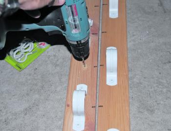STEP 6. With all ten alternatively spaced saddles on the second length of timber, it is now time to affix the cup hooks. Drill a hole around a centimetre deep centrally on the pine stud at every second (vacant) spot.